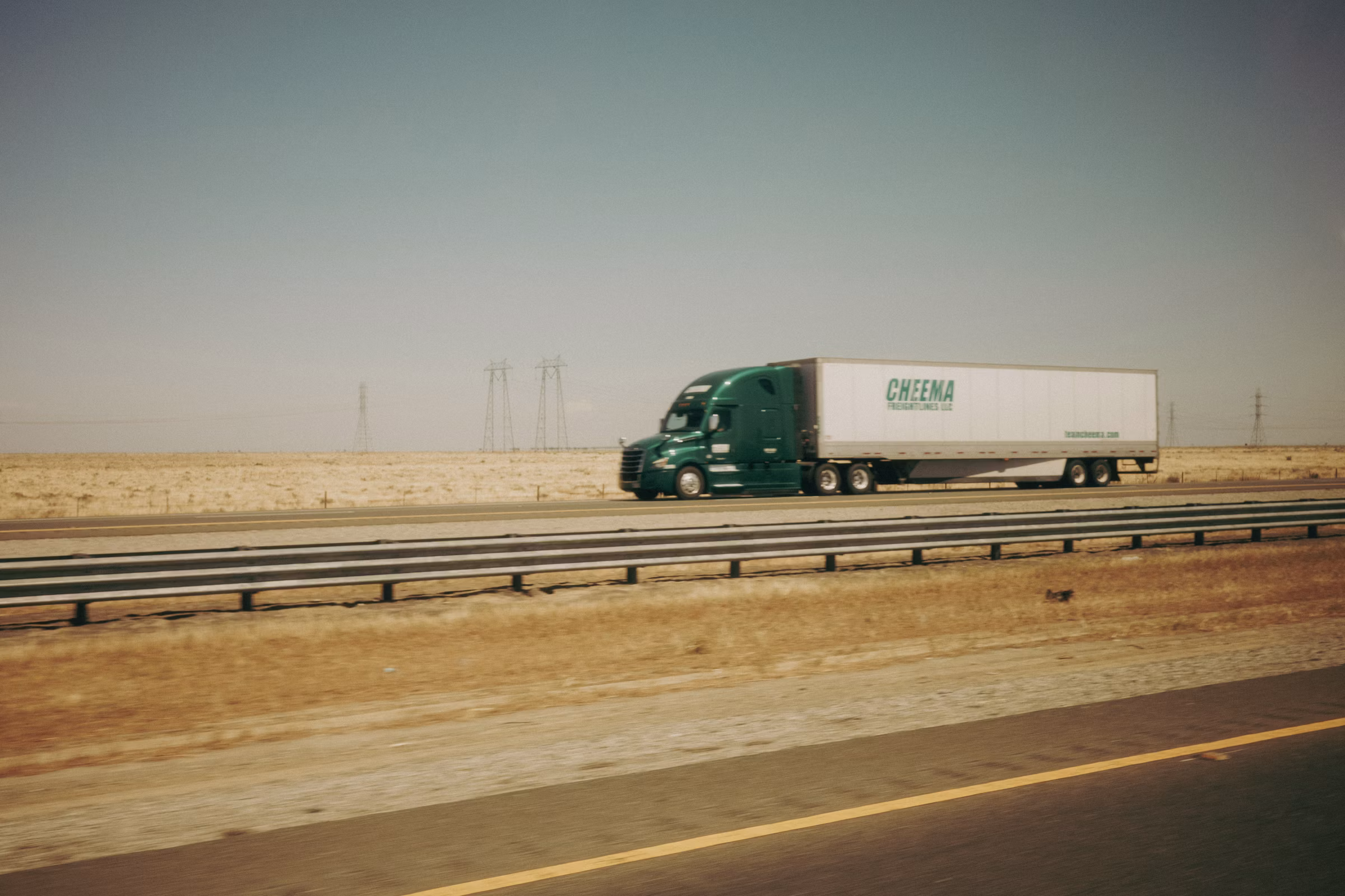 Heavy truck moving across an open highway at golden hour